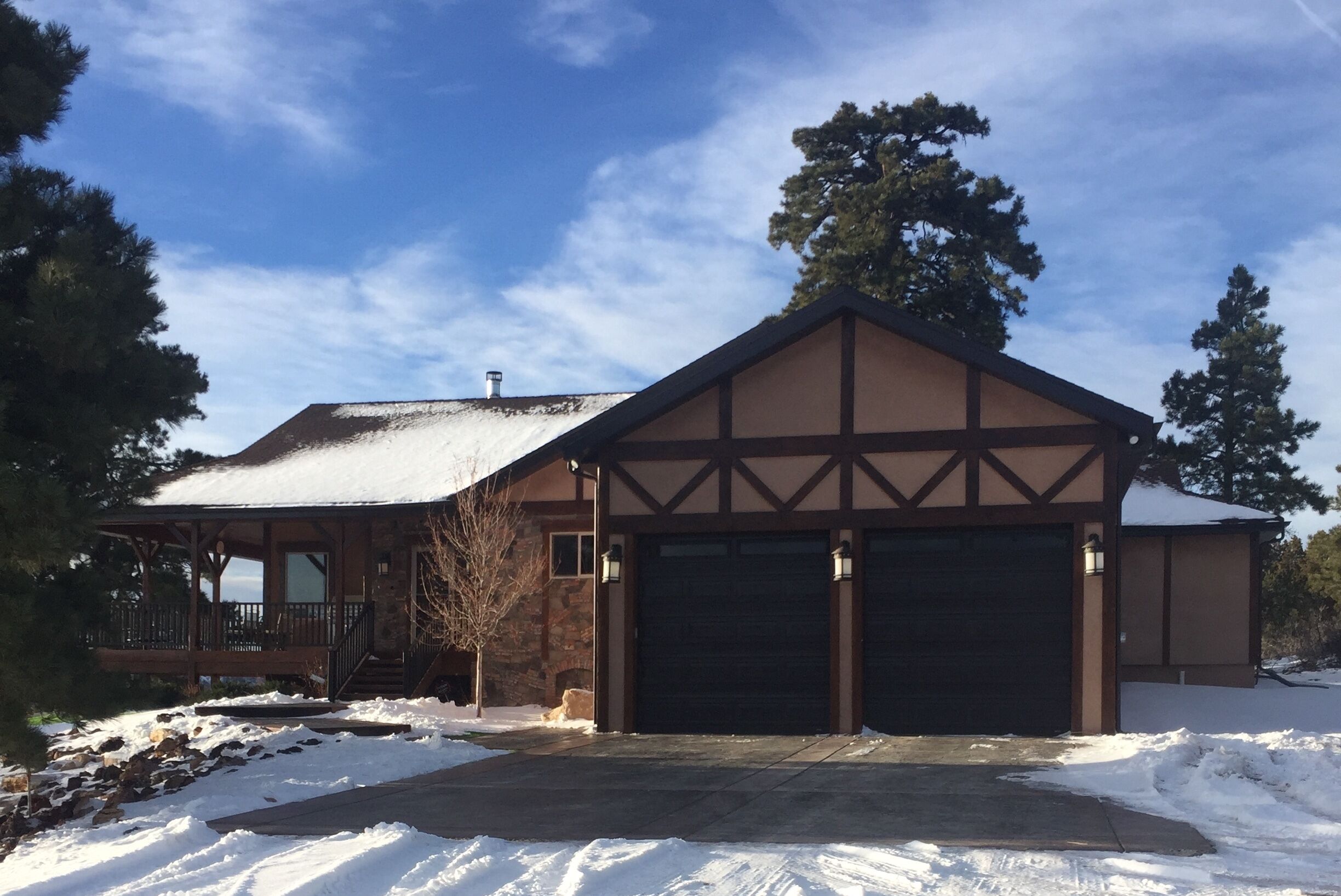 A two-story house with a garage, a covered porch, and a stone exterior.