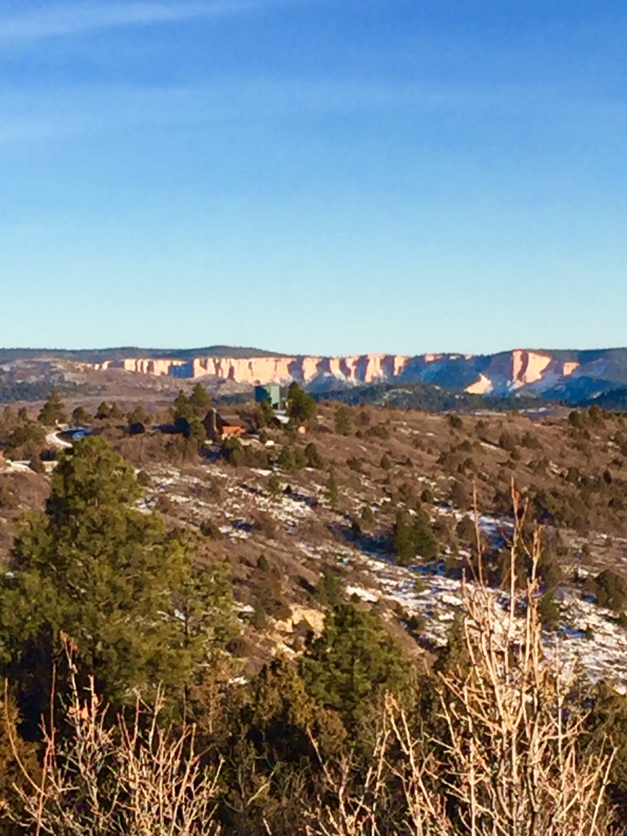 Un paysage montagneux à la végétation clairsemée, sous un ciel dégagé.