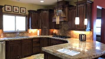 A kitchen with dark wooden cabinets, a granite countertop, and a window with natural light.