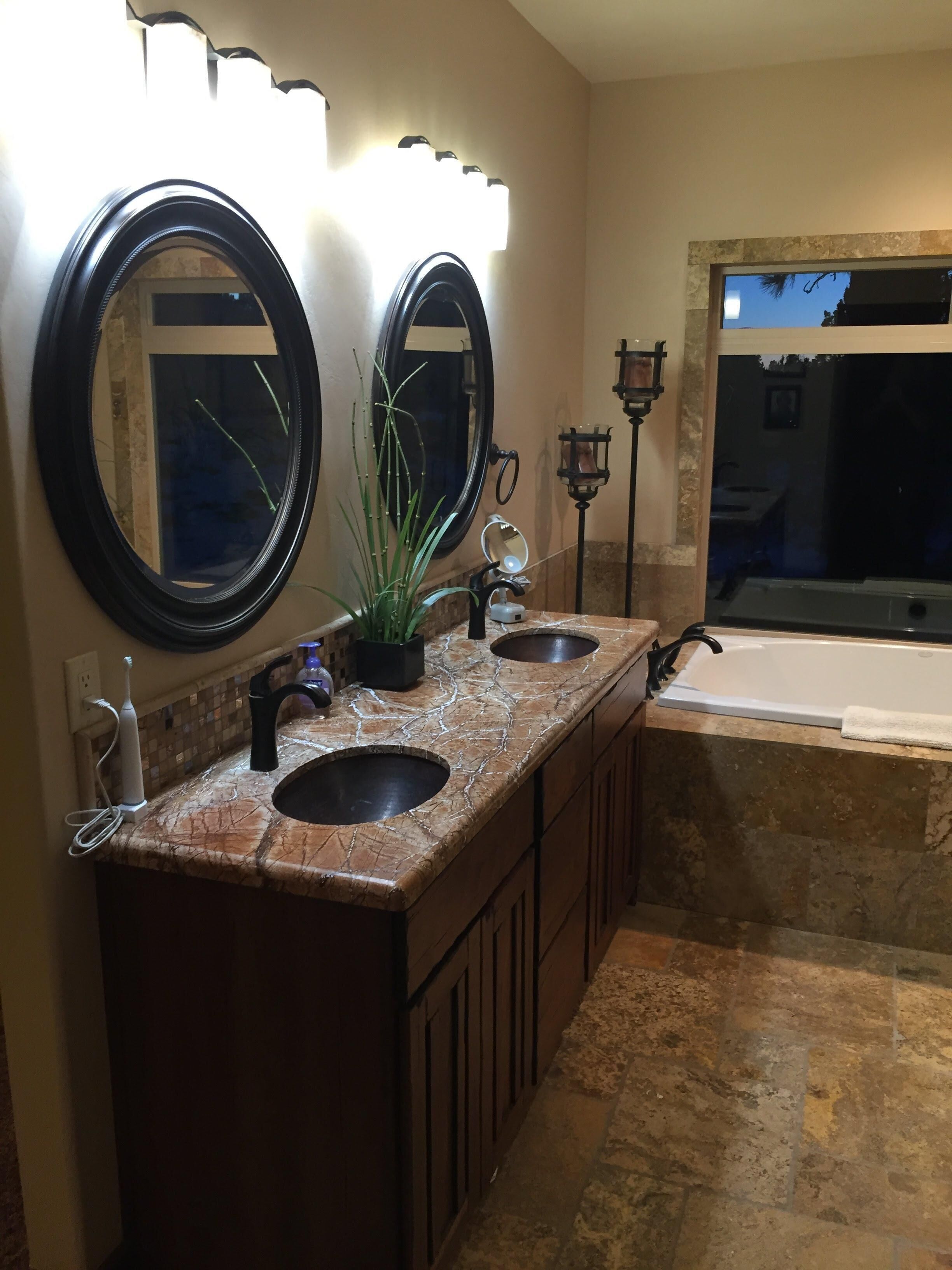A bathroom with two sinks, a large mirror, and a bathtub.