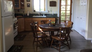 A kitchen with wooden cabinets, a refrigerator, a sink, and a dining table with chairs. - Charming Waimea home on the Big Island- Close To Town!  (Waimea)