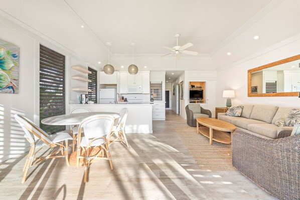 A spacious living area with a sofa, a dining table with chairs, and a kitchen in the background.