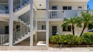 Un immeuble à plusieurs étages doté d’un escalier central, de balcons et d’une entrée fermée par un portail.