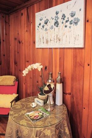Relax in a serene space with a round table, a vase, a candle holder, and a beautiful orchid.
