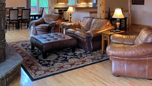 A spacious living room with a high wooden ceiling, leather sofas, a dining area, and a kitchen in the background. - Lodge on the Golf Course in Star Valley Ranch, WY.  Best View and location!! (Star Valley Ranch)