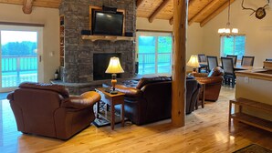 A spacious living room with a stone fireplace, leather sofas, wooden flooring, and a dining area with a wooden table and chairs. - Lodge on the Golf Course in Star Valley Ranch, WY.  Best View and location!! (Star Valley Ranch)