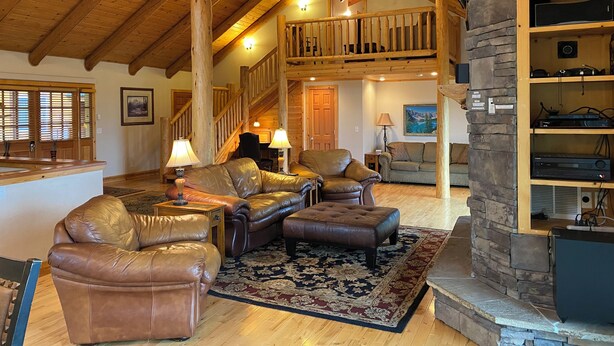 A spacious living area with leather sofas, a wooden staircase, and a stone fireplace. - Lodge on the Golf Course in Star Valley Ranch, WY.  Best View and location!! (Star Valley Ranch)