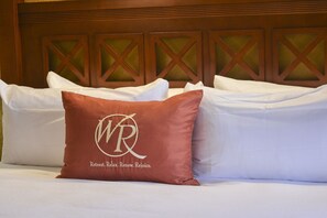 A hotel room with a bed featuring white linens and a single decorative pillow with a logo and text. - BEAUTIFUL STUDIO AT WESTGATE LAKES RESORT & SPA NEAR DISNEY UNIVERSAL SEA WORLD (Orlando)