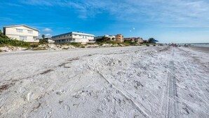 Una playa arenosa con edificios al fondo.