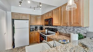 Una cocina moderna con armarios de madera, un refrigerador de acero inoxidable, un microondas y una estufa.