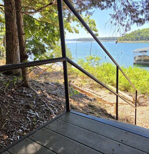 Une terrasse en bois avec une rambarde en métal donnant sur un lac.