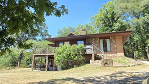 Une maison à deux étages avec une façade en pierre, un balcon et une petite terrasse.