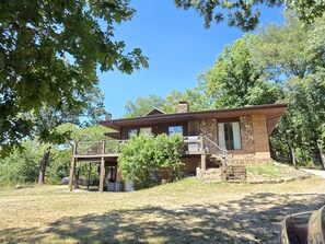 A two-story house with a stone facade, a balcony, and a small deck area.