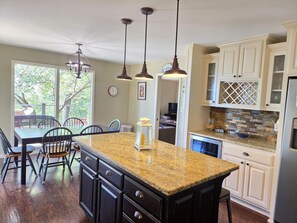 A kitchen with granite countertops, dark cabinetry, pendant lighting, and a view of the outdoors.