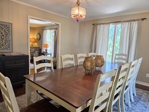 A dining area with a wooden table, white chairs, and two woven vases.