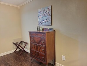 A wooden dresser with drawers and a mirror, a wall-mounted painting of birds, and a small wooden shelf with decorative items. - Lands End-Easy Private, lake access, with amazing lakeview. (Garfield)