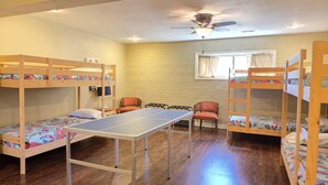 Une pièce avec des lits superposés, une table de ping-pong et un ventilateur de plafond.
