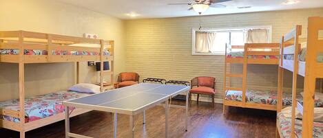 A room with bunk beds, a ping pong table, and a ceiling fan.