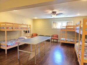 A room with bunk beds, a ping pong table, and a ceiling fan.