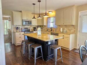 A kitchen with a large island, bar stools, stainless steel appliances, and pendant lighting. - Lands End-Easy Private, lake access, with amazing lakeview. (Garfield)