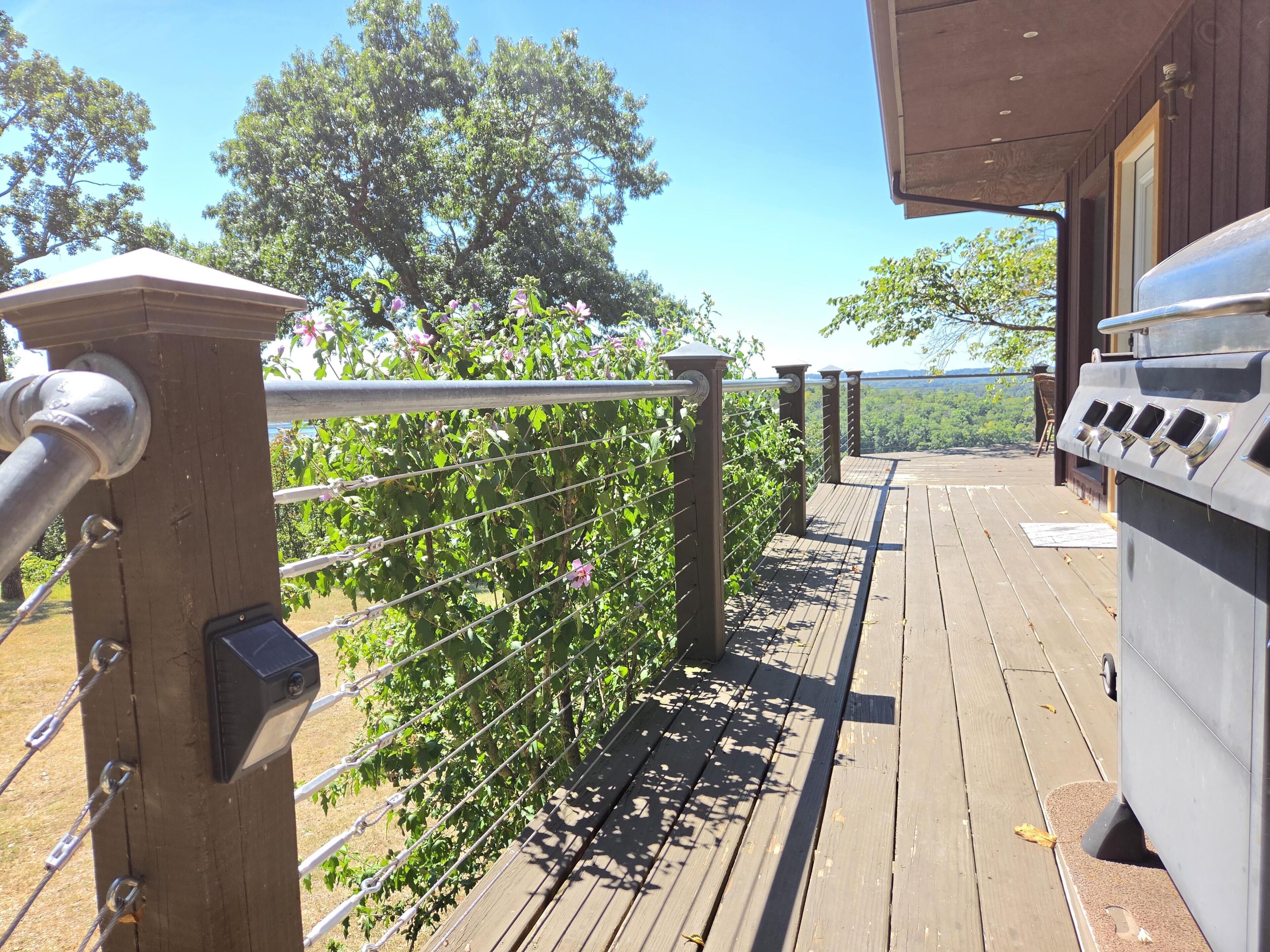 A wooden deck with a barbecue grill and a metal railing.