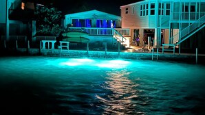 A waterfront property with a dock, a covered boat storage area, and a two-story building with a balcony. - Springs Venture Out Dolphin House #386 with beautiful open water views (Cudjoe Key)