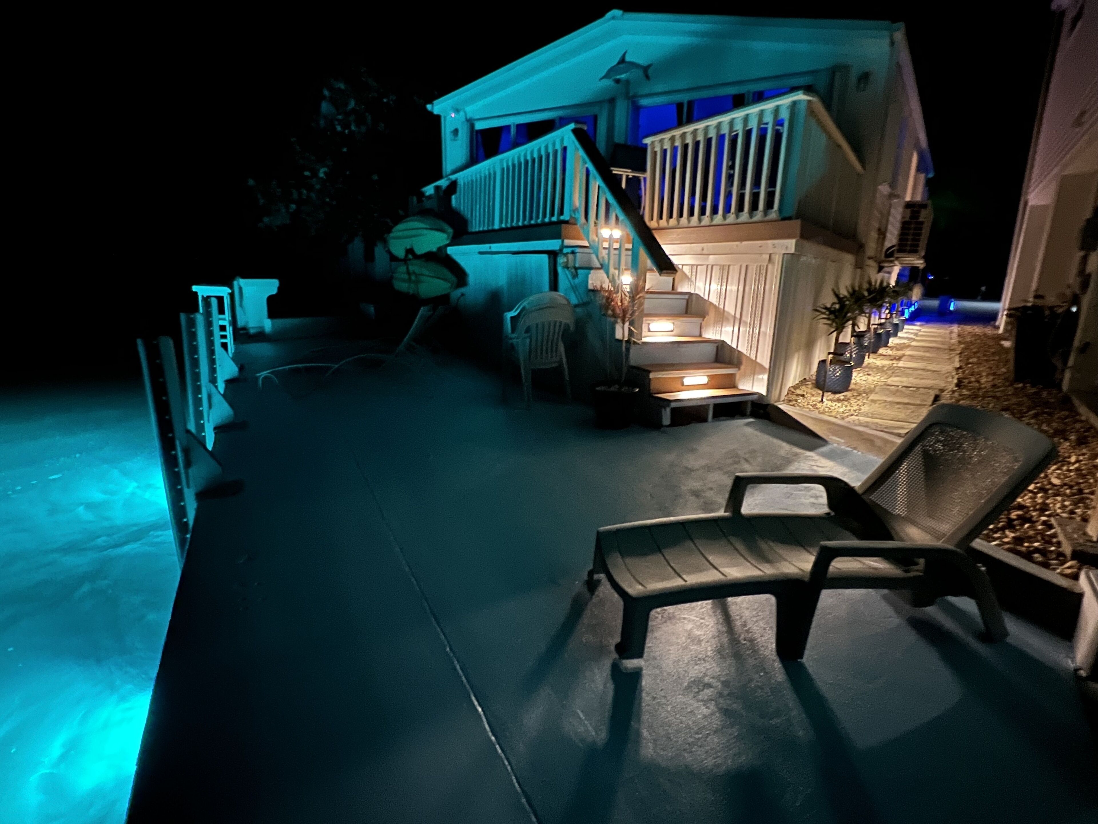 Et hus med overdækket terrasse, udendørs møbler og en trappe til øvre plan.