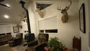 A living room with a fireplace, two deer heads mounted on the wall, a couch, and a coffee table with a plant.