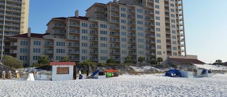 A beachfront hotel with multiple floors, balconies, and a sandy beach area.