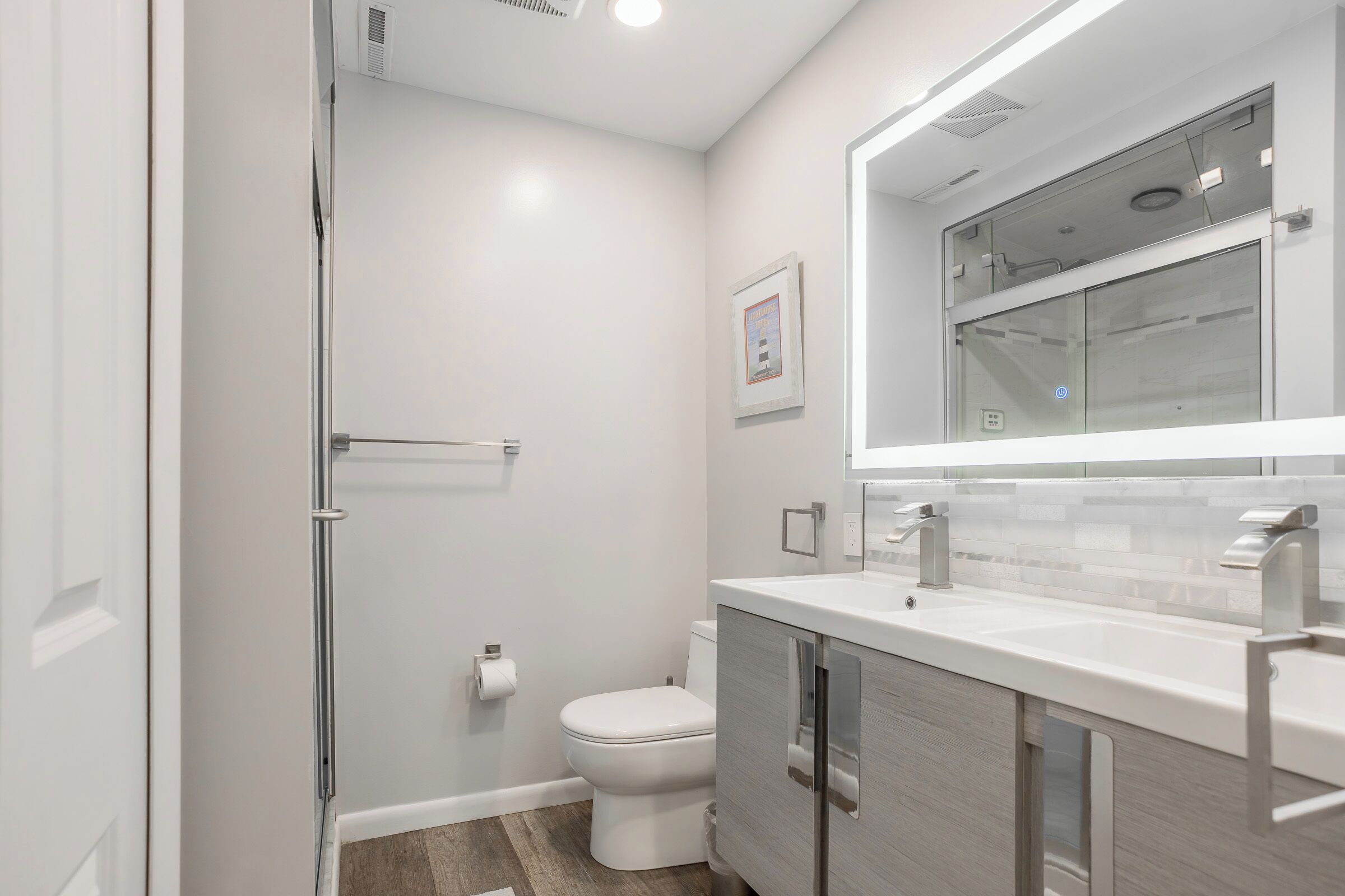 A modern bathroom with a shower, toilet, and vanity.