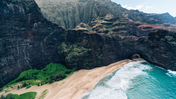 A coastal landscape with a beach, cliffs, and a tunnel entrance.
