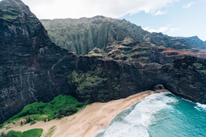 A coastal landscape with a beach, cliffs, and a tunnel entrance.