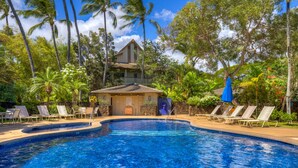 A pool with lounge chairs and a building with a tiled roof.