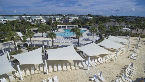 Resort com piscina, guarda-sóis e espreguiçadeiras.
