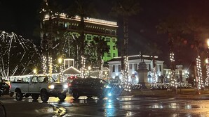 Une place de ville illuminée la nuit, avec des bâtiments et des lampadaires éclairés.