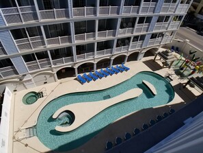 A hotel with a pool area, including a large pool and lounge chairs.
