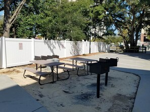 Des tables de pique-nique en plein air, une clôture blanche et des arbres.