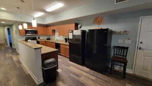 A modern kitchen with wooden cabinets, a black refrigerator, and a granite countertop. - MBV 6Br/5Ba - 304B (Myrtle Beach)