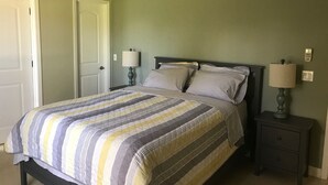 A bedroom with a bed, two bedside tables, a ceiling fan, and a door. - Comfy House Near River And Beach (Sebastian)