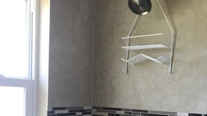 A shower area with a handheld showerhead, a wall-mounted towel rack, and a tiled shower floor. - Comfy House Near River And Beach (Sebastian)