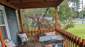 A covered patio with a wooden fence, metal chairs, and a table.