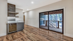 Enjoy cooking in this kitchen with a central island and oven, leading to an outdoor deck with forest views.