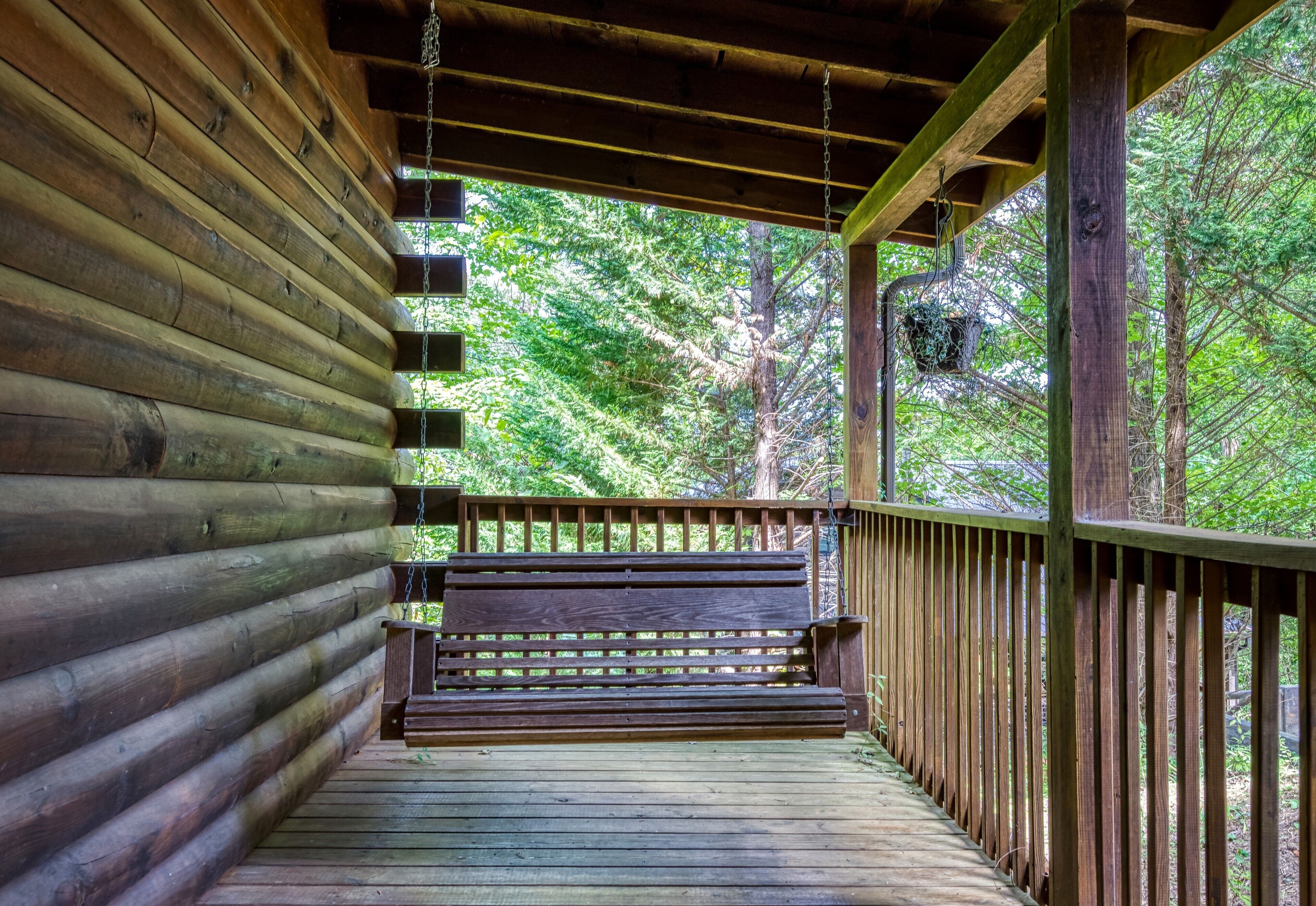 Une cabane en rondins de bois avec un banc en bois sur une véranda.