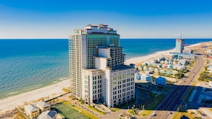 A high-rise hotel with a modern design, located near a beach with a clear view of the ocean.