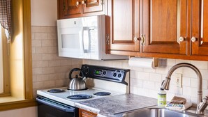 Una cocina con armarios de madera, una estufa blanca, un microondas y un lavabo.