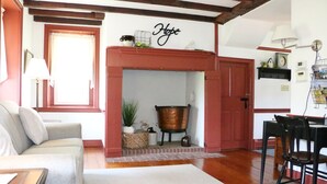 Una sala de estar acogedora con chimenea, un sofá, una mesa de comedor con sillas y una lámpara.