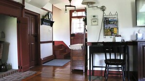Una cocina con suelo de madera, una silla negra, una lámpara blanca y un mueble para revistas.