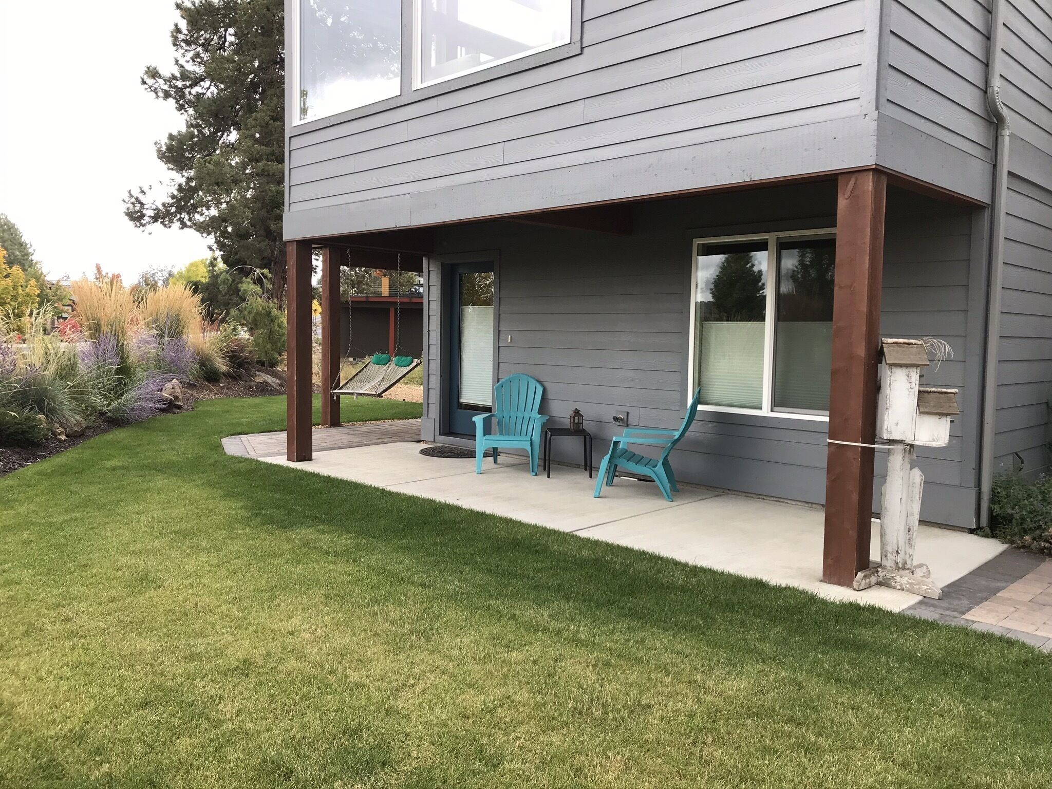 Une maison dotée d’un patio couvert, de deux chaises et d’une balançoire.