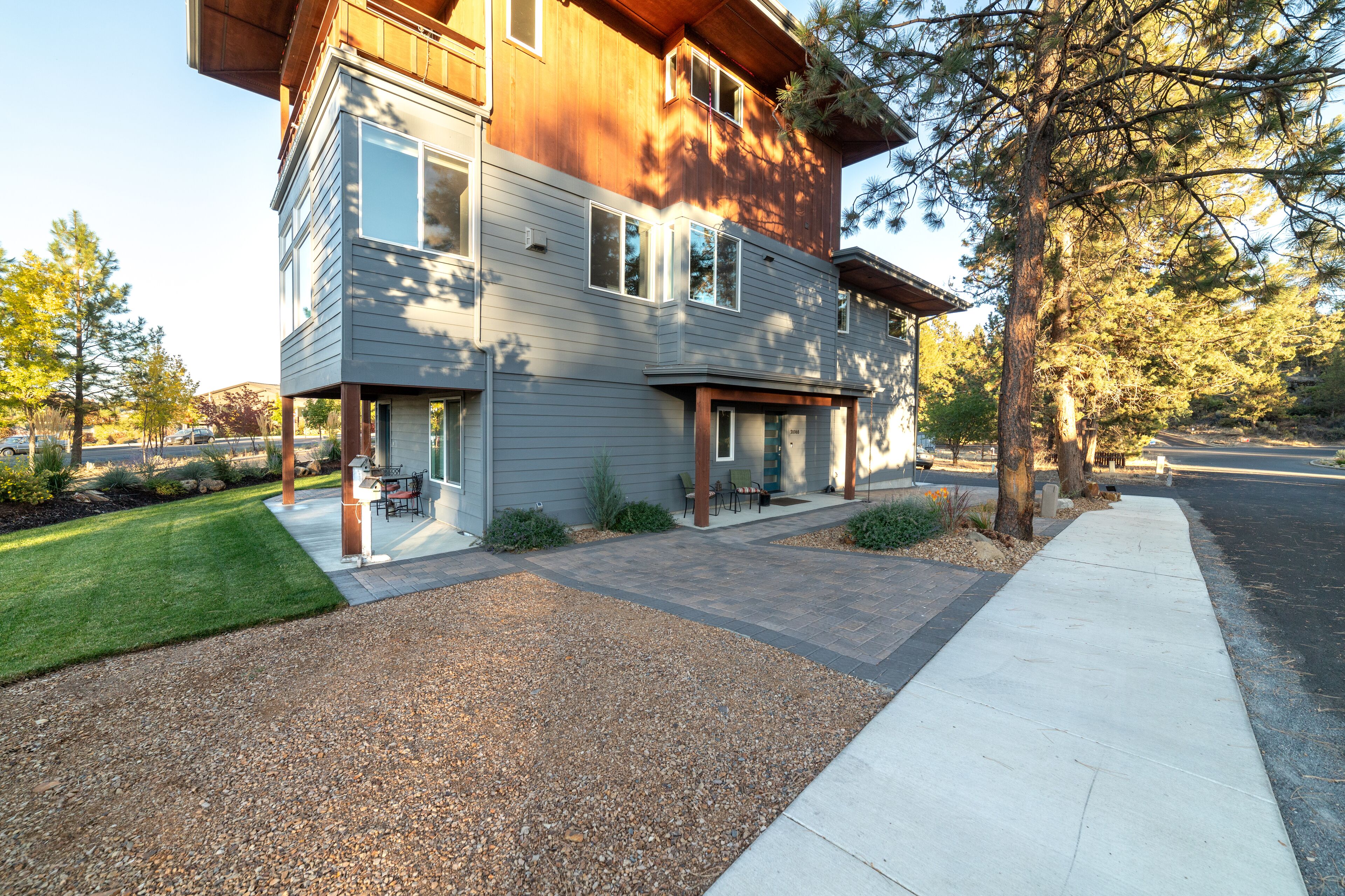 Uma casa moderna de dois andares, com varanda coberta, entrada por acesso individual e gramado bem cuidado.