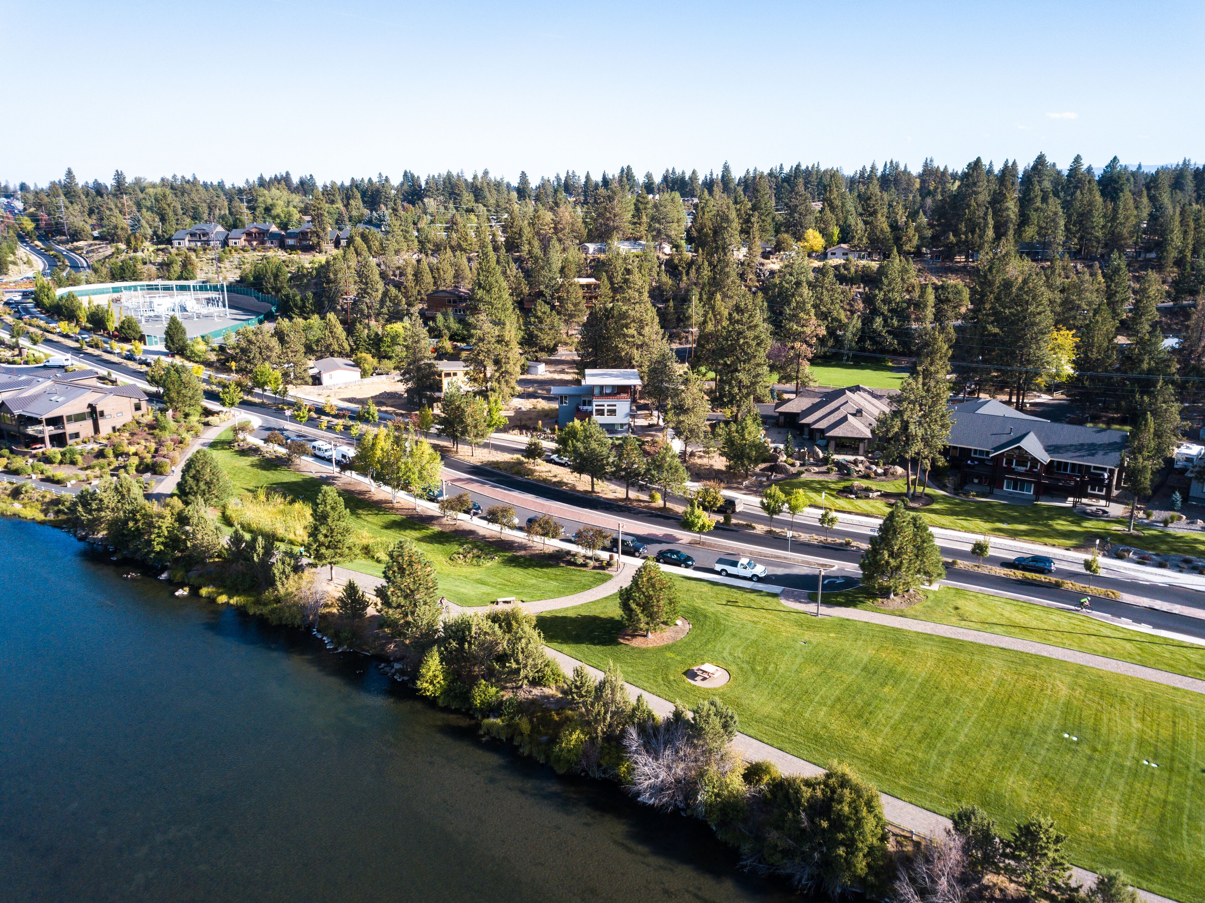 An aerial view of a residential area with houses, a road, and a body of water.